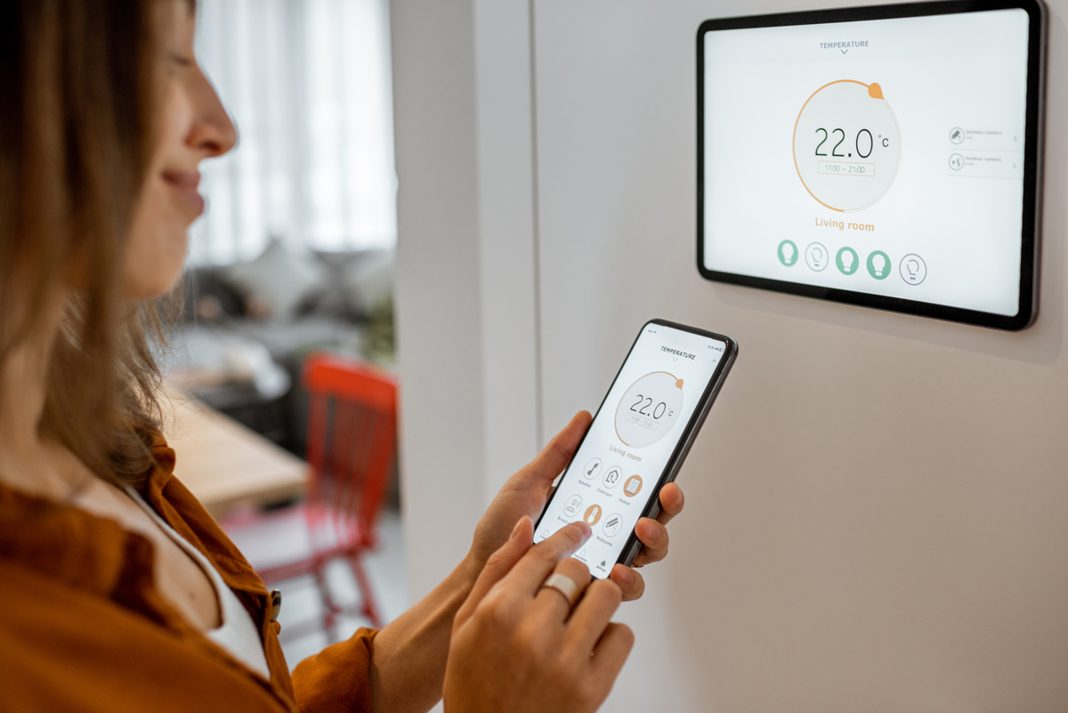 Woman controlling heating with a smart devices smart thermopstat