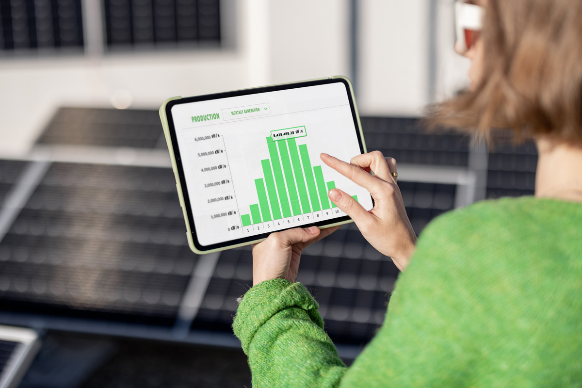 Woman monitors energy production from the solar power plant with a digital tablet smart thermostats energy monitoring