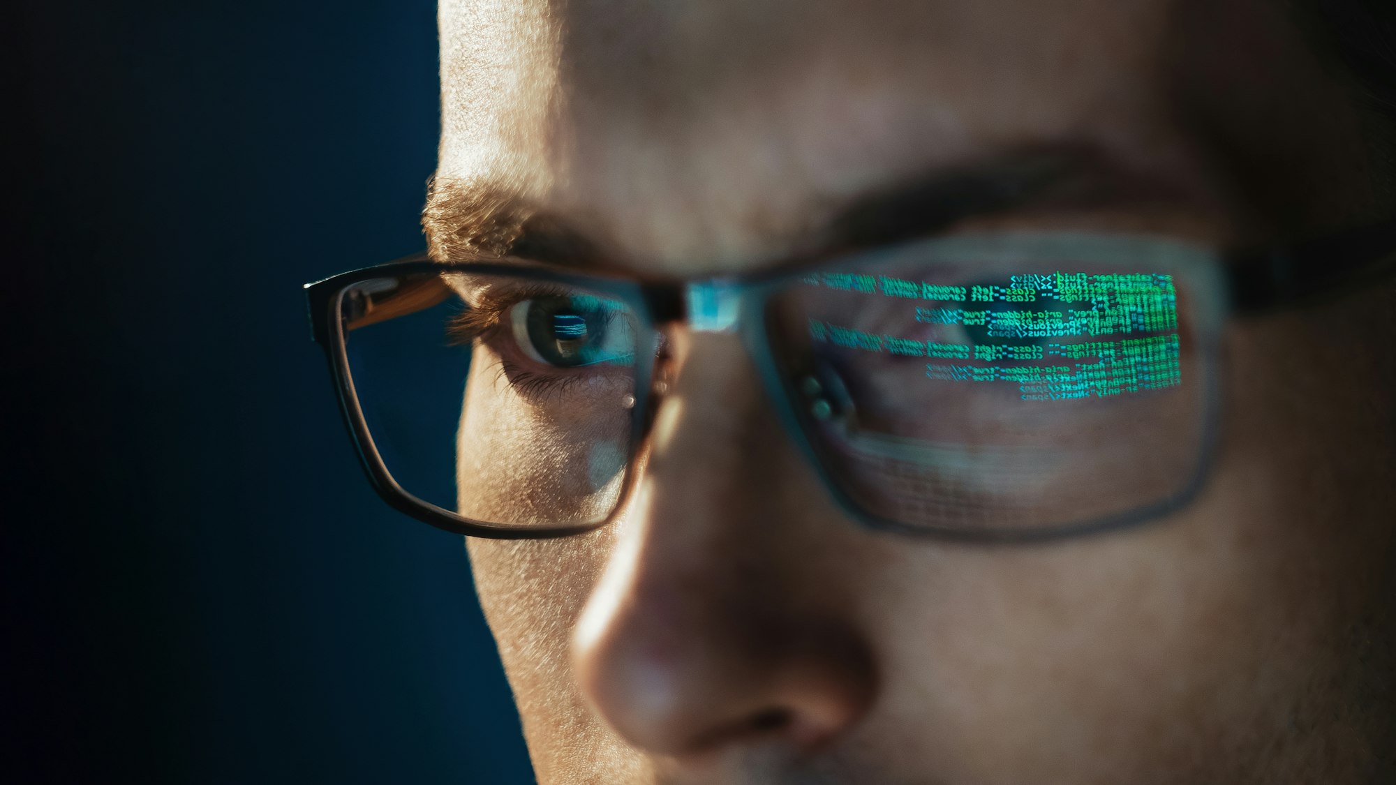 Close-up portrait of focused software engineer wearing eyeglasses