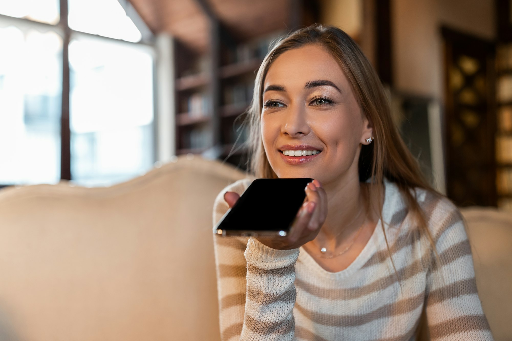 Portrait of happy woman using voice assistant on cellphone