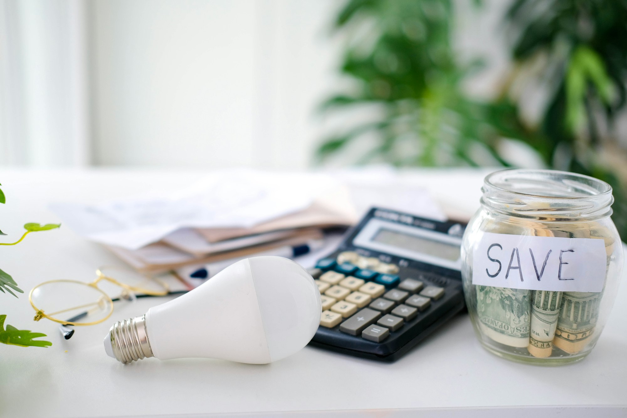 Saving energy and money concept. LED lamp,calculator and piggy bank with dollar money.