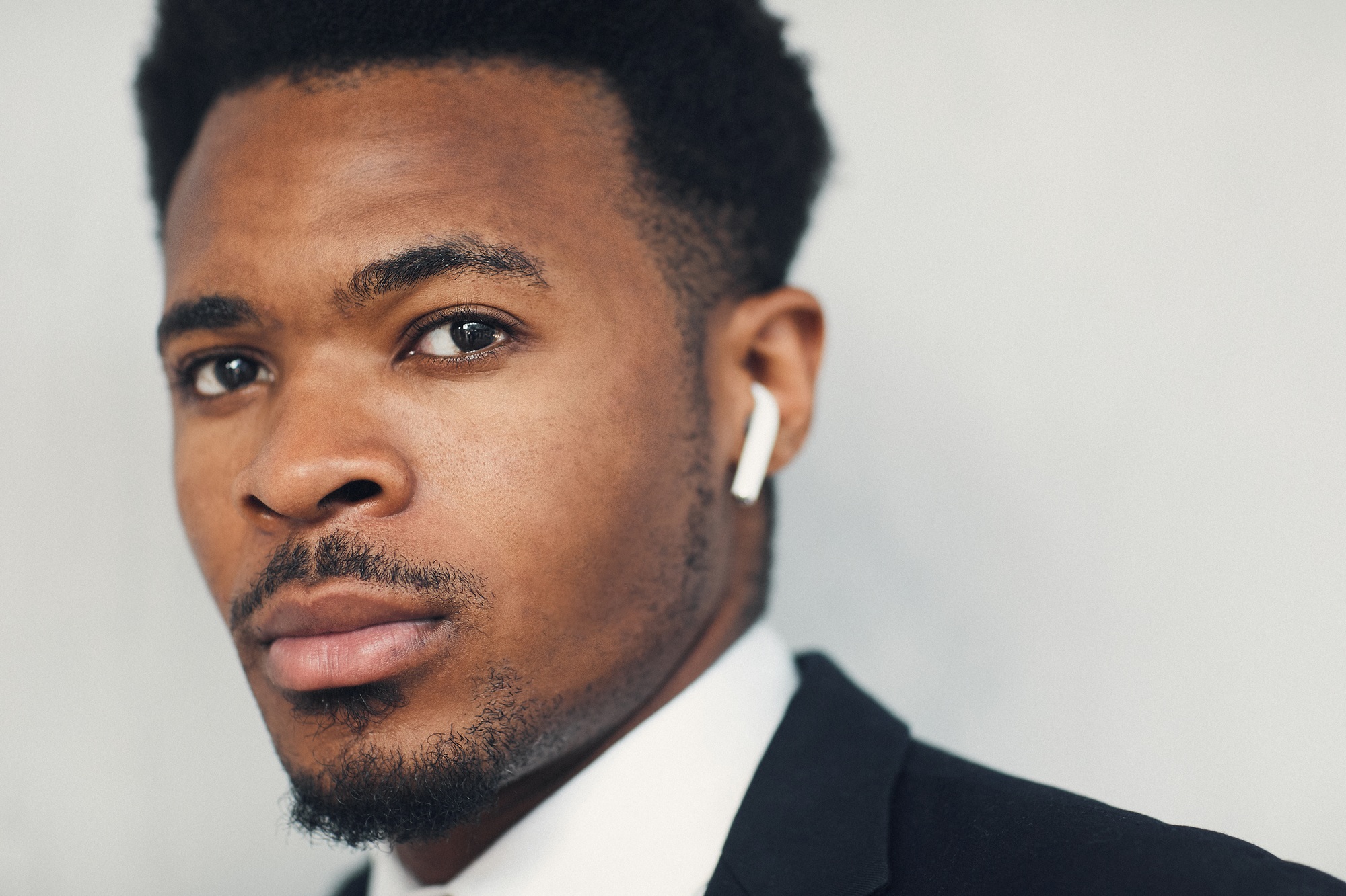 Serious young businessman using Bluetooth earbuds