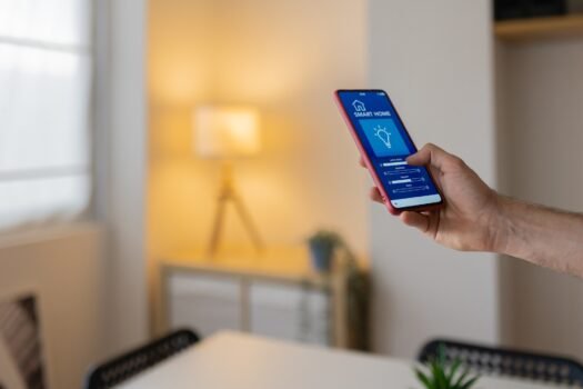Man Using Smart Home App On Smartphone To Control Lighting