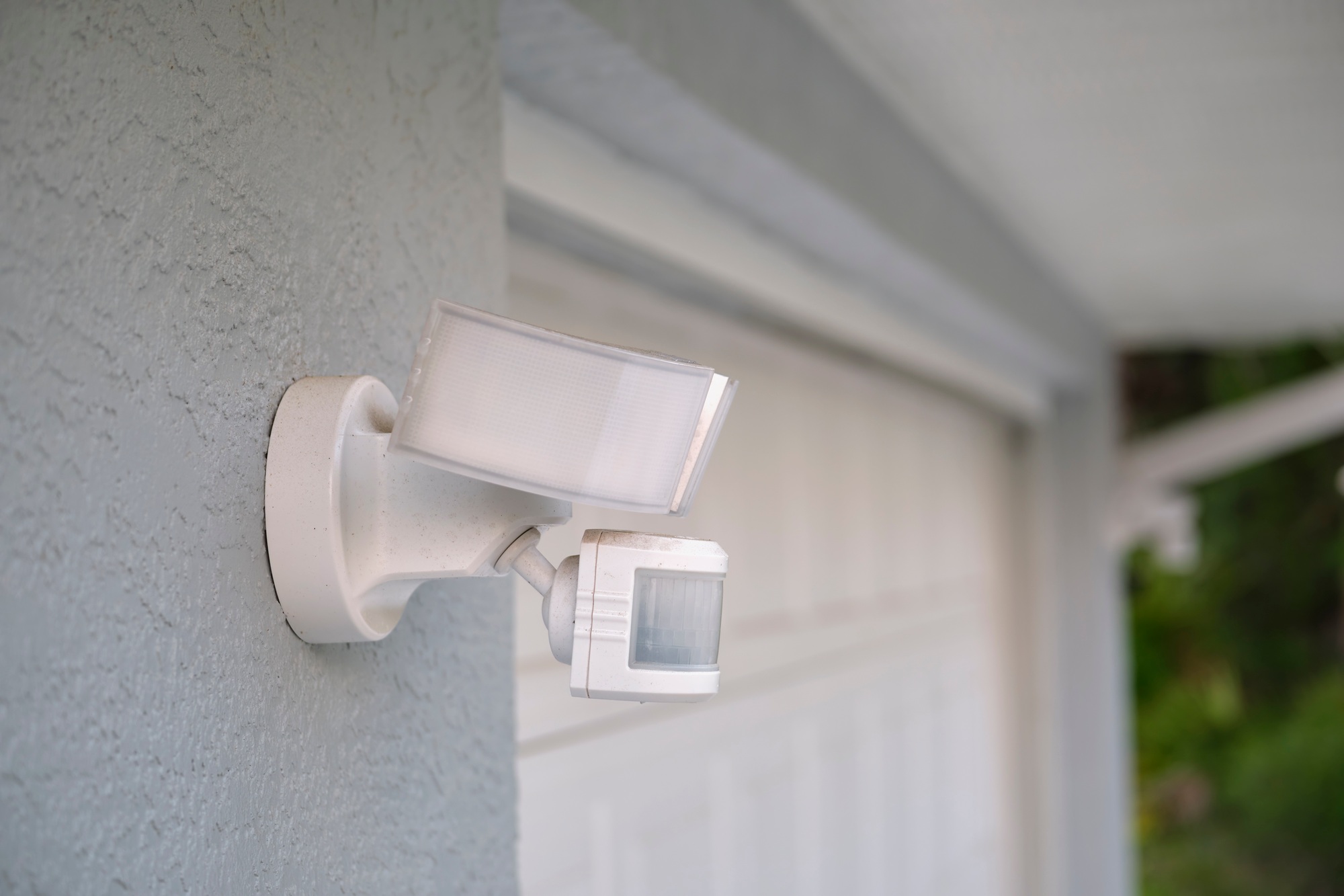 Motion sensor with light detector mounted on exterior wall of private house