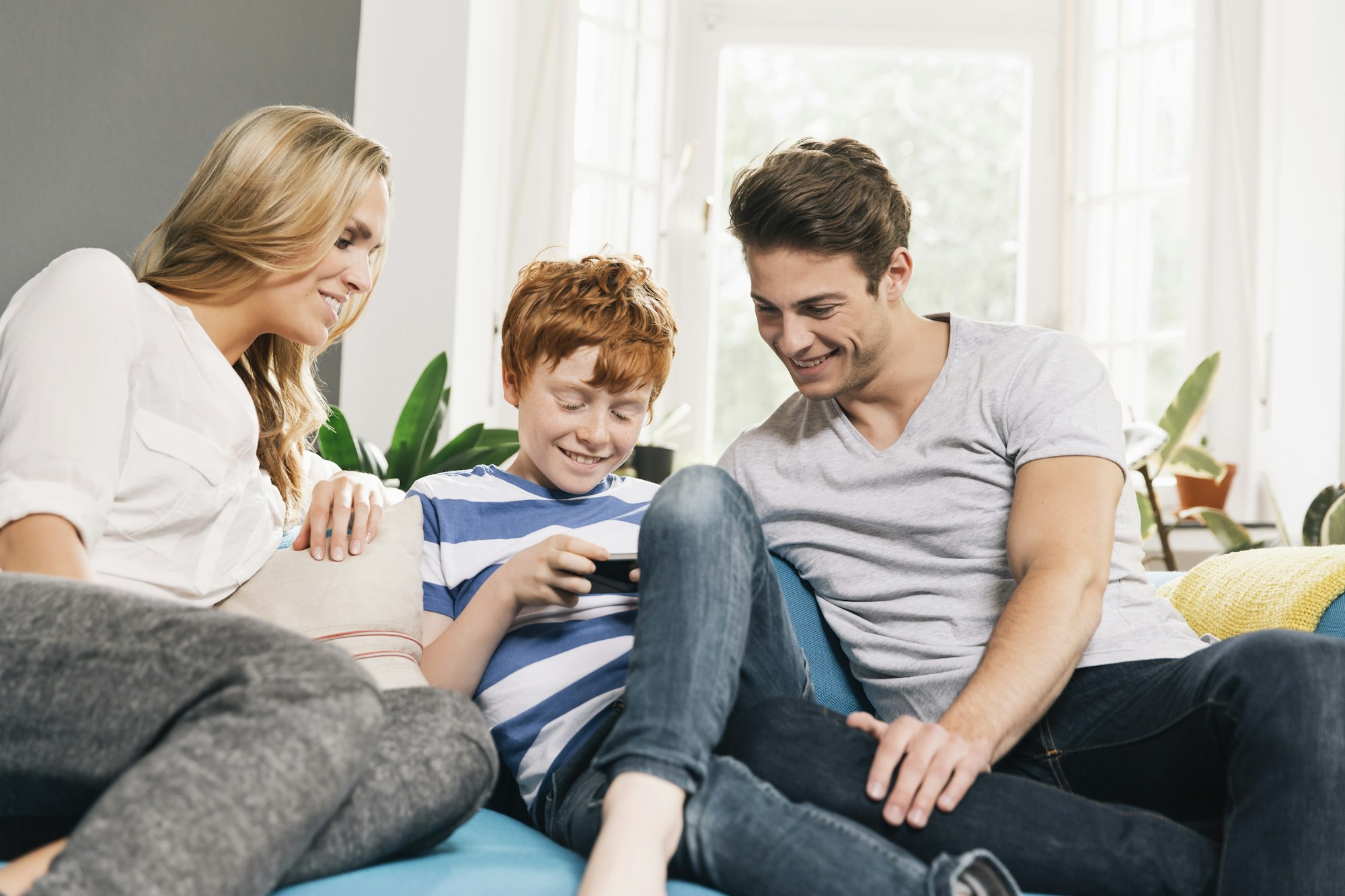 Young family sitting on couch looking at smartphone